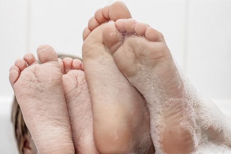 Closeup of wrinkeled feet on edge of bubble bathtubの写真素材