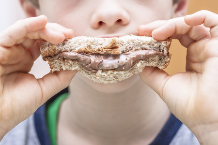 Closeup of boy eating sweet sandwich with chocolate creamの写真素材