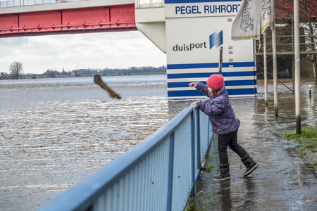 DUISBURG / GERMANY - JANUARY 08 2017 : Little girl surprised by the river Rhine flooding the promenade in Ruhrortのeditorial素材