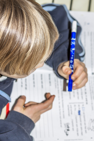 Left handed young working on his homeworkの写真素材