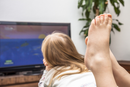 Little girl watching television on the sofaの写真素材