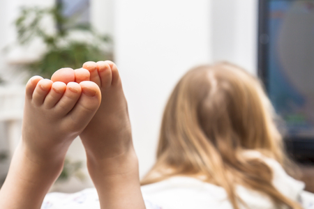 Little girl watching television on the sofaの写真素材