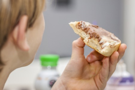 Closeup of boy eating sweet sandwich with chocolateの写真素材