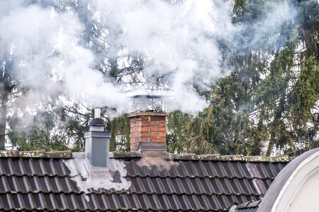 Smoking chimney and pipe on the top of a houseの写真素材