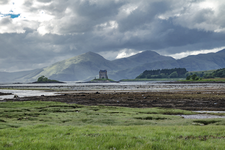 Castle Stalker seen from Jubilee Bridge in Appin with breathtaking view of mountains in the backgroundの写真素材
