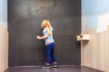 Cute little girl writing on empty chalkboardの写真素材