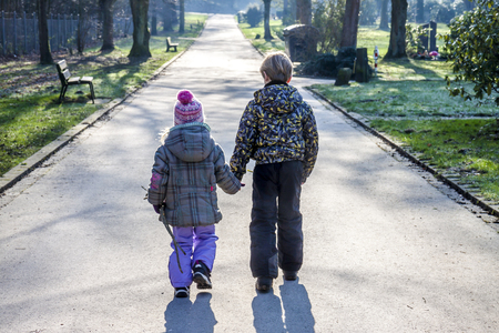Little boy and girl holding hands and walking a long straight pathの写真素材