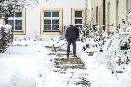 Man sweeping snow from the pavementの写真素材