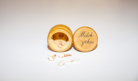 Collection of extracted milk teeth in front of wooden box - Translation: milk teeth