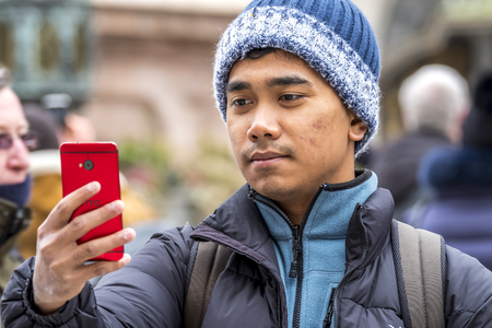Munich / Germany - February 15 2018: Asian boy taking selfies with her smartphoneのeditorial素材