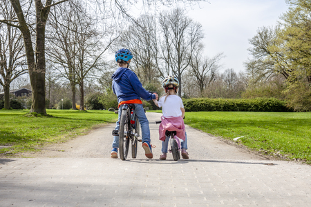 Boy and girl holding hands while on their bicycles.の写真素材