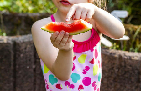 Cute little girl eating watermelon in the summertimeの写真素材