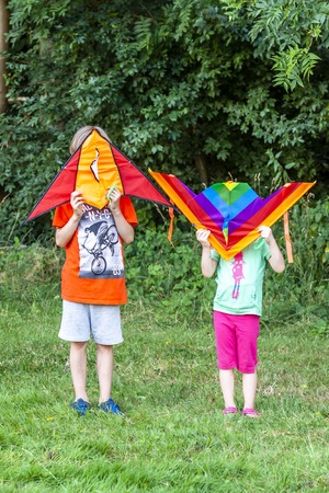 Boy and girl having fun flying a kite in summerの写真素材