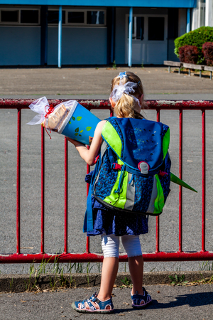 Little girl standing in front of the school building holding her candy coneの写真素材