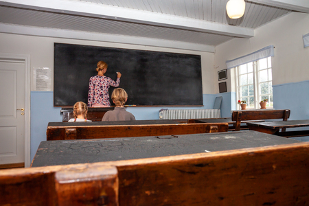 Concept of public primary school education with young boy and girl listening to the female teacher.の写真素材