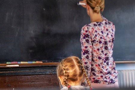 Concept of public primary school education with young girl listening to the female teacher.の写真素材