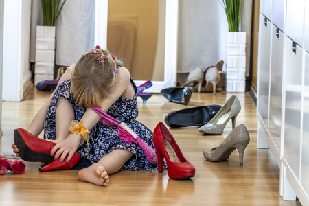 Little girl wearing big high-heeled mothers shoesの写真素材