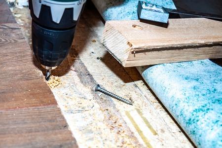Man using drill machine while installing new wooden laminate flooring at home.の写真素材