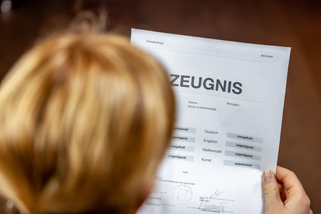 Mother holding a very bad German school certificate in her hands Translation: certificate day of birth disciplines music reading religion german english mathematics art maths insufficient grade f deficient satisfyingの写真素材