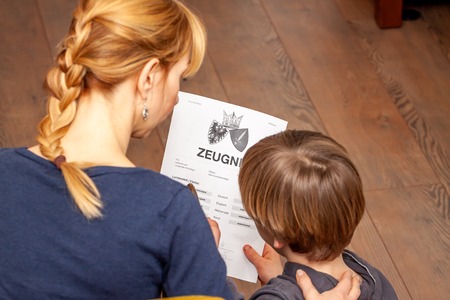 Mother comforting son despite the bad school certificate - Translation: certificate day of birth disciplines music reading religion german english mathematics art maths insufficient grade f deficient satisfyingの写真素材