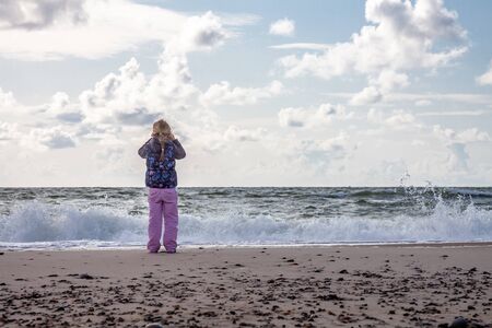 Little girl standing on the beach in the Netherlandsの写真素材