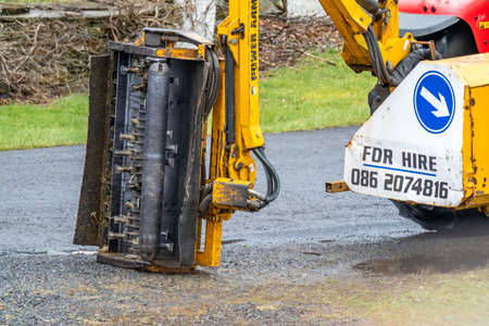 Donegal / Ireland - March 11 2020 : Huge machine cutting trees , bushes and gras along the roadのeditorial素材
