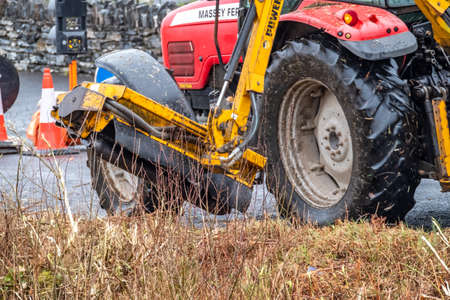 DONEGAL / IRELAND - MARCH 11 2020 : Huge machine cutting trees , bushes and gras along the road.のeditorial素材
