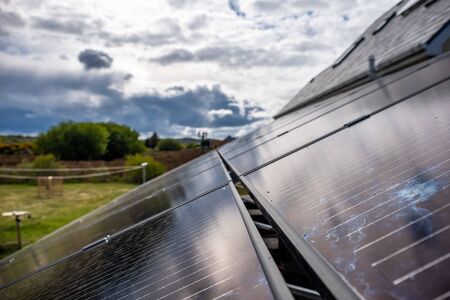 Photovoltaic panels installed on a rack next to house with solar panels for hot waterの写真素材