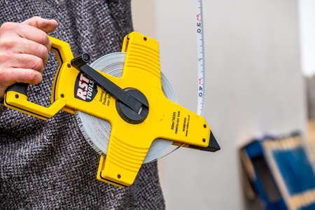 Donegal / Ireland - May 15 2020 : Construction worker using his long surveyor tape meterのeditorial素材