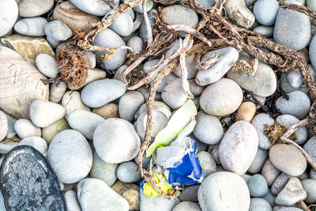 Plastic Pollution and bottom of a foot found at gravel beachの写真素材