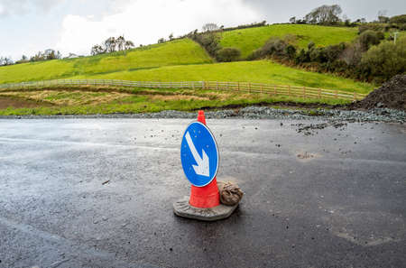 Traffic cones with white arrow on blue ground showing direction at roadworks