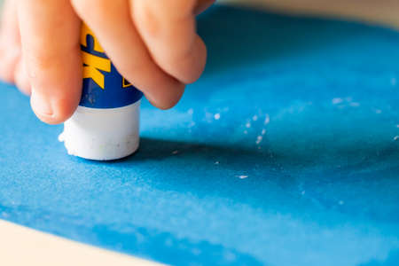Applying glue stick to the blue paperの写真素材