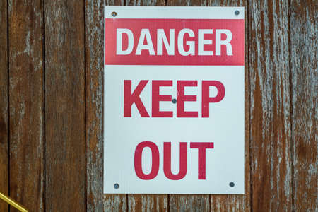 A red and white danger keep out sign attached to a doorの写真素材