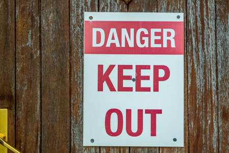A red and white danger keep out sign attached to a doorの写真素材