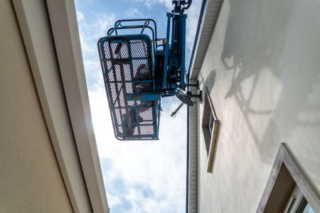 Worker on a aerial access platform, cherry picker, cleaning house