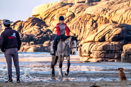 Burtonport, County Donegal, Ireland - December 18 2021 : The ward family is riding their horses on the beachのeditorial素材