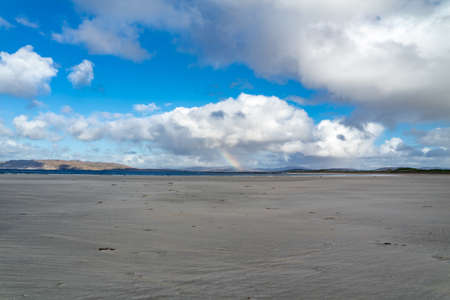 Beatiful rainbow shining through the huge commulus cloudの写真素材