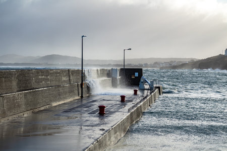 Waves crashing against the pier at Portnoo harbour after Storm Franklin - County Donegal, Republic of Irelandの写真素材