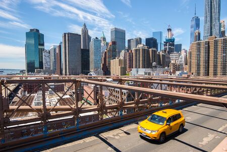 New York Manhattan skyline from the Brooklyn Bridge with yellow taxiの写真素材