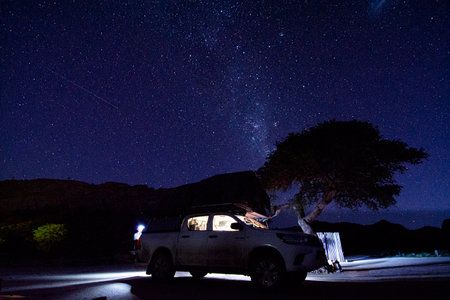 Milky way over a tent located on the roof of a pickup car in the Namib desert of Namibia.の写真素材