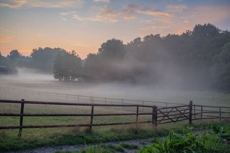 Fog rising over the farmhouse after sunset.の写真素材