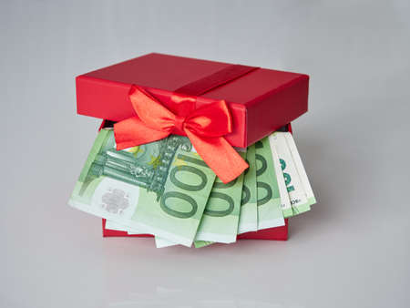 A red gift box filled with Euro currency money. Banknotes with a nominal value of 100 euros.