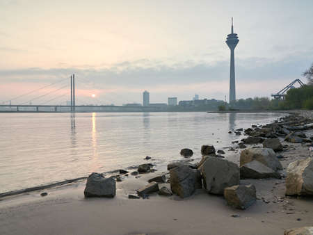 Sunrise on the banks of the river Rhine in Dusseldorf. Dusseldorf city skyline overlooking the Rheinkniee bridge, the old town and the Rheinturm.の写真素材