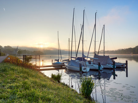 A wonderful sunrise over Lake Baldeneysee in the city of Essen. Moored sailboats in the foreground. Landscape photographyのeditorial素材