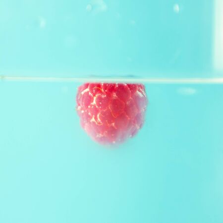 Beautiful raspberry in water with bubbles. Organic healthy food. Sweet berries. Summer harvest. Ripe raspberries isolated. Red berries background. Clean wet raspberry macro.の写真素材