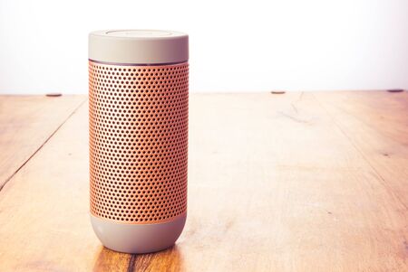 Elegant portable wireless speaker isolated on wooden background