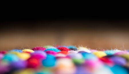 Dark wooden background and colourful fluffy wool ballsの写真素材
