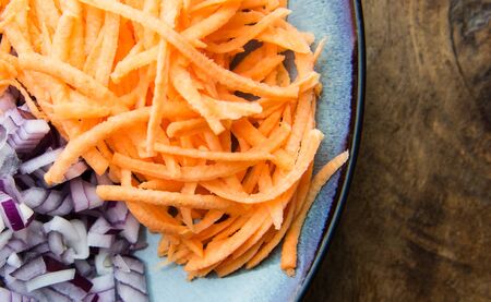 Grated sweet potatoes and onions on a clay plate. Food concept.の写真素材