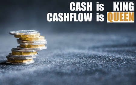 Cash is king, cashflow is queen phrase on a dark background with money, coins on a sideの写真素材