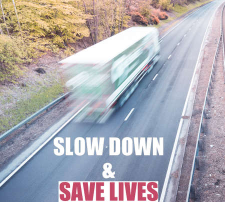 Slow down and save lives phrase on a background with blurred lorry on a dual motorway.